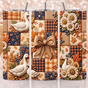 Könnte beinhalten: Ein zylindrischer Becher mit Strohhalm, der ein Patchwork-Design aus weißen Gänsen, orangefarbenen und braunen Herbstblättern, blau-orangen Karomustern, weißen Gänseblümchen und blauen Beeren zeigt, mittig mit einer großen beigen Stoffschleife.