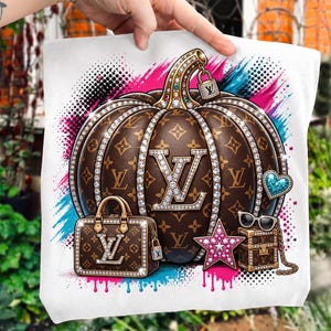 May include: A white tote bag featuring a brown pumpkin graphic with a repeating monogram pattern, accented by sparkling rhinestone trim. The design includes a matching handbag, a pink star, a blue heart, sunglasses, and a small padlock.