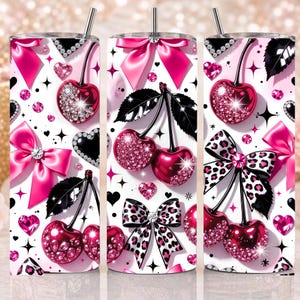 May include: A cylindrical tumbler with a straw featuring a white background patterned with pink cherries, black and pink bows, leopard print accents, and sparkling heart-shaped gems. The design includes scattered black star shapes and glittery details.