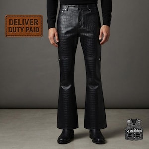 May include: Black trousers featuring a textured crocodile skin pattern, a high-waisted fit, and a flared leg silhouette. The pants include a front button closure and silver-toned hardware accents, paired with black leather shoes.
