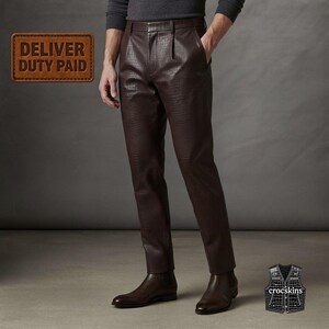 May include: Dark brown trousers featuring a textured crocodile skin pattern, a buttoned waistband, and a straight-leg cut. The image includes a rectangular brown label with the text DELIVER DUTY PAID and a small icon of a vest with the text crocskins.