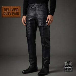 May include: Black trousers featuring a textured crocodile skin pattern, a straight-leg cut, and large cargo-style pockets on the thighs. The trousers are paired with black leather boots. A brown rectangular label reads DELIVER DUTY PAID.