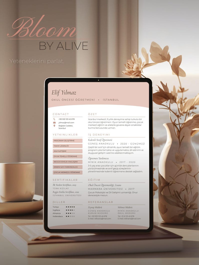 May include: A digital tablet displaying a resume with the name "Elif Yilmaz" and contact information. The tablet is set on a wooden surface next to a coffee cup and a decorative vase with dried flowers. The resume is in Turkish.