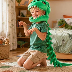 May include: A bright green plush dinosaur costume featuring a large headpiece with soft teeth and a long, segmented tail with spikes. The costume is made of a soft fabric and is designed to be worn over the head and down the back, creating a full-body dinosaur appearance for imaginative play.