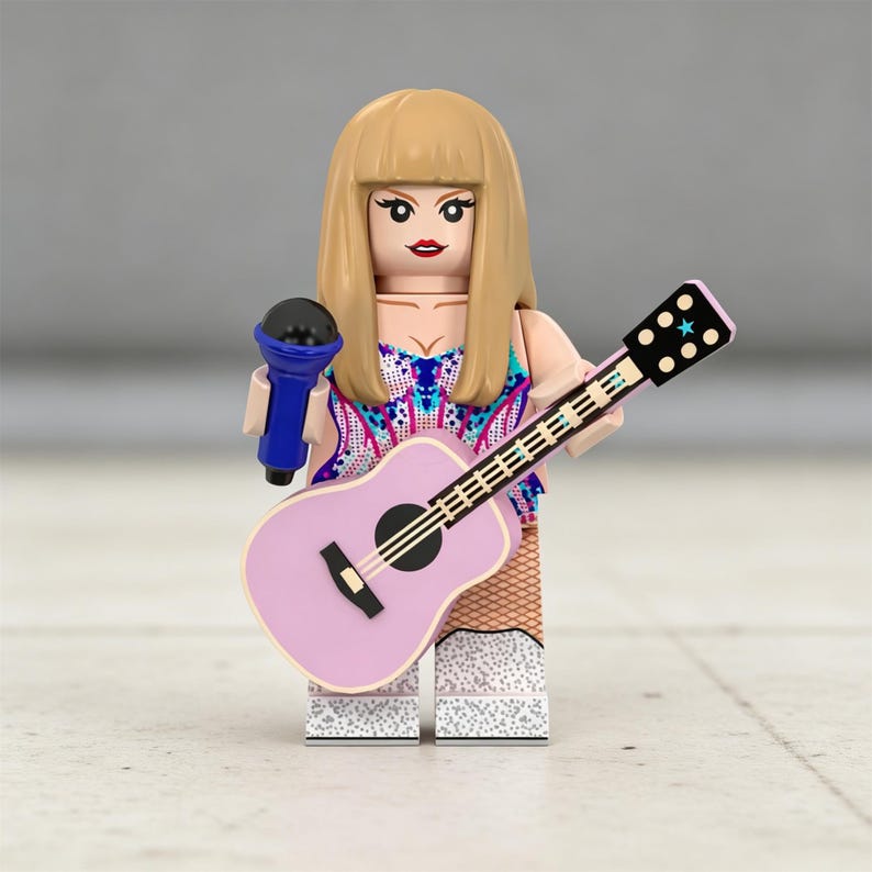 May include: A Lego figurine of a pop star holding a blue microphone and a pink guitar. The figurine has blonde hair, red lipstick, and a colorful top. The guitar has black strings and a black sound hole.