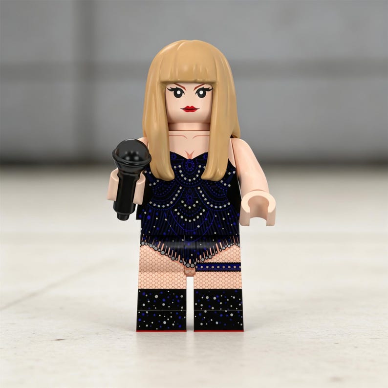 May include: A Lego figurine of a performer with blonde hair and red lipstick, holding a black microphone. The figurine wears a dark blue outfit with a decorative pattern and black boots with white dots.
