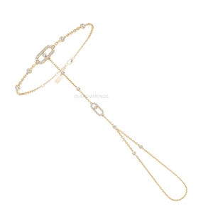 Könnte beinhalten: Ein Handkettchen aus Gold mit zwei ovalen Gliedern, die mit kleinen weißen Diamanten besetzt sind. Die feine Kette ist mit gleichmäßig verteilten, in Gold gefassten runden Diamanten verziert, was ein durchgehendes, elegantes Design ergibt.