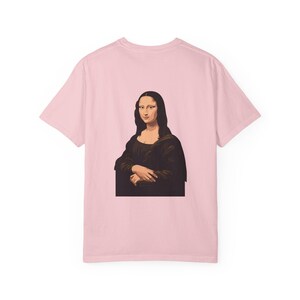 The back of a pale pink t-shirt displays a graphic of the Mona Lisa portrait.