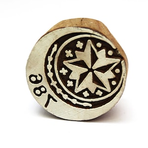 May include: A round wooden printing block featuring a carved design of a central eight-pointed star surrounded by small crosses and a crescent moon shape. The number 88 is clearly engraved on the left side of the circular face of the block.