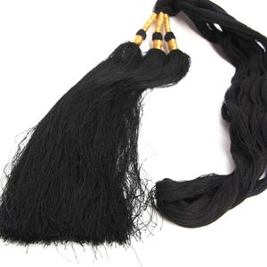 May include: A decorative black tassel featuring three distinct bundles of fine black thread. Each bundle is secured at the top with a metallic gold-colored cylindrical accent, creating a structured and uniform appearance for this textile accessory.