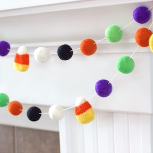 May include: A Halloween garland with felt balls in orange, green, purple, white and black. The garland also features felt candy corn decorations.
