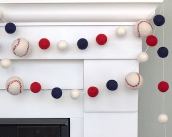 May include: A felt ball garland with red, white, and blue balls, including baseball-themed balls. The garland is strung across a white fireplace mantel.