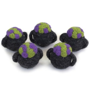May include: Five felt cauldron ornaments with green and purple accents. The cauldrons are black and have a round shape.