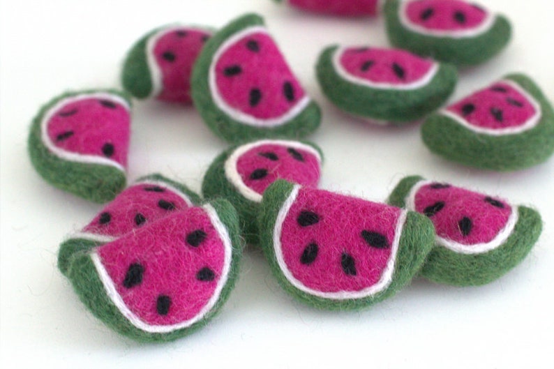 May include: A collection of felt watermelon slices in various shades of green, pink, and white. The watermelon slices are hand-crafted and have a realistic appearance.