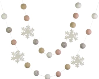 May include: A garland of white, pink, and beige felt balls with white felt snowflakes hanging between the balls.
