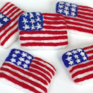 May include: Five felt American flags in red, white, and blue. Each flag has a blue field with white stars and 13 red and white stripes.
