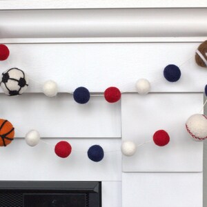 May include: A garland of white, red and blue felt balls with felt sports balls including a baseball, basketball, football and soccer ball.