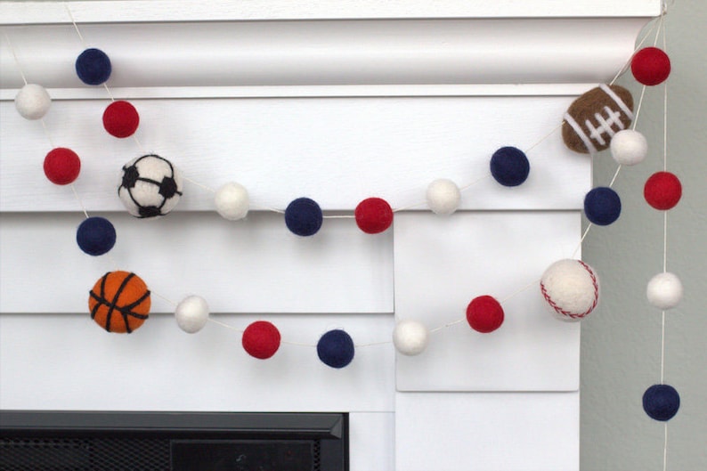 May include: A garland of white, red and blue felt balls with felt sports balls including a baseball, basketball, football and soccer ball.