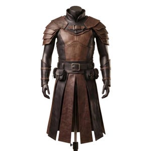 K&ouml;nnte beinhalten: Ein R&uuml;stungsset aus braunem und schwarzem Leder mit geschichteten Schulterteilen, einer Brustplatte mit Schnallenverschluss, Armschienen und einem G&uuml;rtel mit zwei Taschen. Der untere Teil besteht aus langen, vertikalen Lederbahnen.