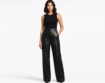 Puede incluir: Una camiseta negra sin mangas de cuello redondo combinada con pantalones de talle alto en piel sintética negra. Los pantalones presentan una silueta de pierna ancha, una cintura estructurada con trabillas y costuras verticales visibles.