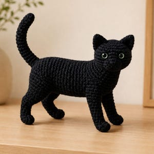Peut inclure: Une figurine de chat noir réalisée en fil crocheté, présentant une posture debout avec la queue levée, des oreilles pointues et deux yeux ronds vert clair. La texture du fil est visible sur tout le corps, créant un aspect doux et détaillé pour cet animal en peluche fait main.