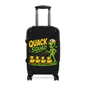 May include: Black rolling suitcase with a graphic of an alien leading a line of yellow ducklings. The text "QUACK SQUAD" is in yellow and green. The alien is wearing a hat and holding a leash.