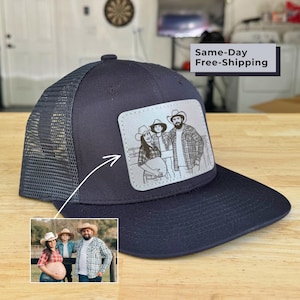 May include: A black trucker hat featuring a rectangular patch with a laser-engraved line art illustration of a family of three wearing cowboy hats. The patch depicts a pregnant person, a child, and an adult standing together in plaid shirts.