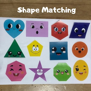 May include: A white rectangular sheet featuring the text Shape Matching and twelve colorful geometric shapes with cartoon faces, including a blue heart, purple rectangle, red hexagon, blue parallelogram, green triangle, yellow pentagon, blue square, orange circle, pink heptagon, purple star, green octagon, and yellow oval.