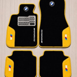 Può includere: Set di quattro tappetini neri per auto con finiture gialle e il logo BMW. I tappetini hanno un accento giallo sugli angoli inferiori sinistro e destro con il logo M Performance e un poggiapiedi color argento.