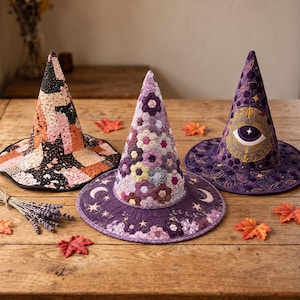May include: Three pointed hats made of quilted fabric. The left hat features a black, pink, and orange geometric pattern. The center hat has a purple hexagonal floral pattern with moon and star motifs. The right hat is purple with an eye design.