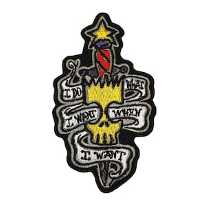 May include: An embroidered patch with a yellow skull and a red, white, and blue dagger. The skull is surrounded by a black banner with the text "I DO WHAT I WANT WHEN I WANT".