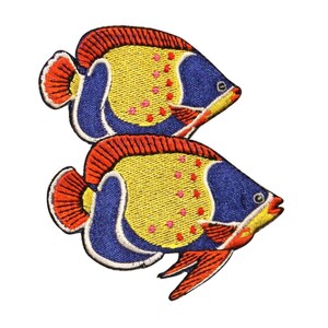 Può includere: Due toppe ricamate da stirare a forma di pesce giallo, blu e arancione. I pesci sono rivolti verso il lato destro dell'immagine.