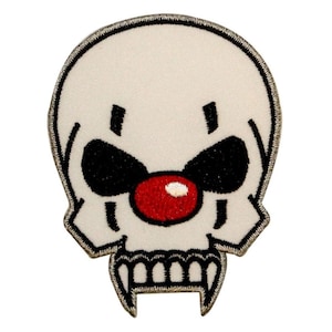 May include: White skull with a red clown nose and black eyes. The skull has a toothy grin.