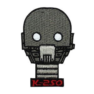 May include: Embroidered patch featuring a stylised robot head with white eyes and a grey and black body. The text "K-2SO" is embroidered in red below the robot head.