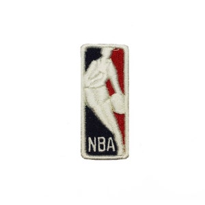 May include: A white embroidered patch with the NBA logo. The logo features a basketball player dribbling a ball in front of a red, white, and blue background. The text "NBA" is below the player.