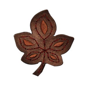 May include: A brown leather leaf with a detailed orange embroidered design. The leaf has a pointed tip and a stem.