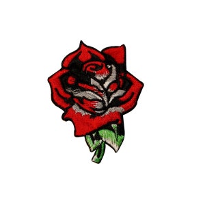 May include: Embroidered patch featuring a red rose with black and white detailing. The rose has green leaves at the base. The patch is designed to be sewn or ironed onto fabric.