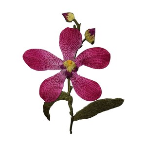 Peut inclure: Une fleur d'orchidée rose avec un centre jaune et des feuilles vertes. La fleur est brodée avec un motif détaillé.