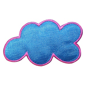 Può includere: Una toppa a forma di nuvola blu con un contorno rosa. La toppa è realizzata in un tessuto morbido e testurizzato.