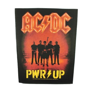 May include: A black and red AC/DC band patch with the band's logo and the words "PWR UP" in yellow. The band members are silhouetted in front of a red and orange background.