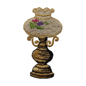 May include: A gold and white embroidered lamp with a floral design. The lamp has a round base and a decorative top.
