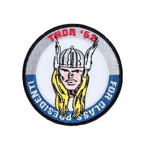 May include: A round, blue, white, and gray embroidered patch with the text "THOR '62" and "FOR CLASS PRESIDENT". The patch features a cartoon image of Thor, the Norse god of thunder, wearing a helmet and cape.