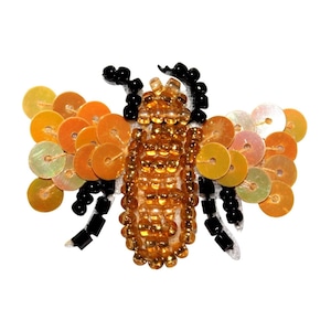 May include: A beaded bee with a gold and brown body and black legs. The bee has iridescent orange and yellow wings.