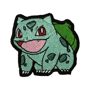 May include: Green and red embroidered patch of a cartoon character with a large mouth and a green shell on its back.