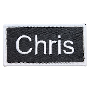 May include: Black name tag with white stitching around the edges. The name "Chris" is embroidered in white on the tag.