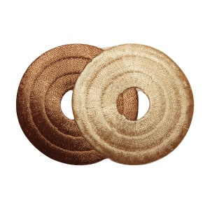 May include: Two round, embroidered fabric patches. One is brown with concentric circles and the other is beige with concentric circles.