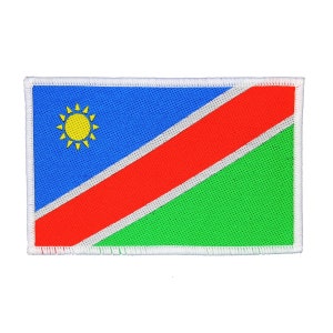 May include: A rectangular patch with the flag of Namibia. The flag is blue with a white diagonal stripe and a red diagonal stripe. The top left corner of the flag features a yellow sun with 12 rays.