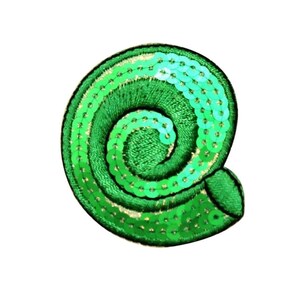 Könnte beinhalten: Grüne Stoffmuschel mit Pailletten. Die Muschel ist mit einem Spiralmuster bestickt.