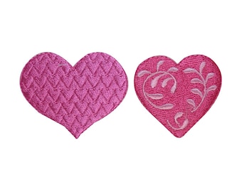 May include: Two pink felt heart-shaped patches. One heart has a textured pattern and the other has a floral design.