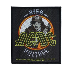 Peut inclure: Patch en tissu noir avec un cercle jaune et orange contenant une image stylisée d'un homme jouant de la guitare avec le texte "AC/DC" et "HIGH VOLTAGE" en lettres jaunes. Le texte "©2015 UNDER LICENSE TO FERRYSCOPE PRODUCTIONS LLC/ EPIC RIGHTS INC" est en bas du patch.